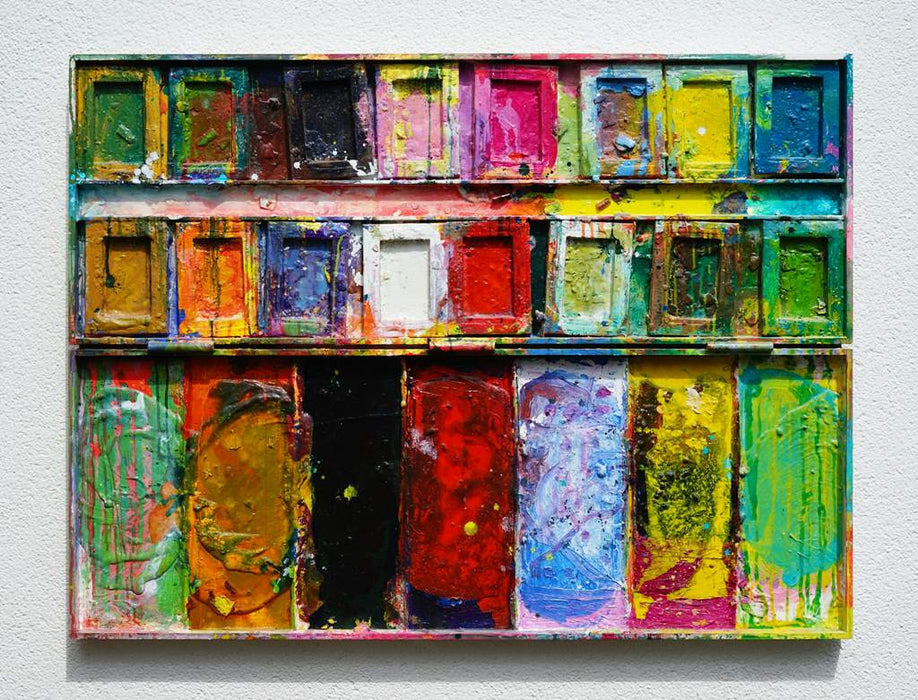 "Der Abschied" zeigt abstrakte Malerei auf einem großen Farbkasten (92 x 112 x 4 cm, in Situation). In den Mischfächer (unten) sind Gelb, Blau, Grün, Rot, Schwarz und Ocker zu sehen. Oben befinden sich 16 quadratische Teller mit den üblichen Farben einer Palette. In den Zwischenräumen sind Kleckse und Flecken sichtbar. Moderne Kunst vom Künstler Mark Hellbusch. ARTLET - Atelier Hellbusch