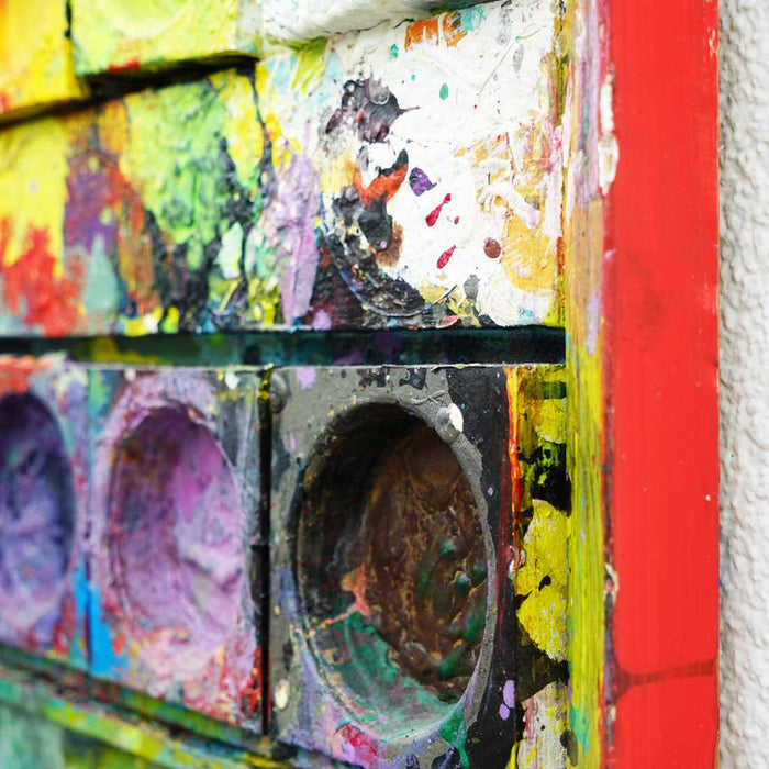 "Am Vesuv" zeigt moderne Kunst auf dem Farbkasten (80 x 80 cm, Seitenansicht). Zu sehen ist das Gemälde in Wiesbaden. In den Mischfächer (unten) sind violette, grüne, weiße und rote Farben. Oben befinden sich 12 Farbteller mit den bunten Farben eines Farbkastens. In den Zwischenräumen sind Farbkleckse und -flecken sichtbar. Moderne Kunst. ARTLET - Atelier Hellbusch. 