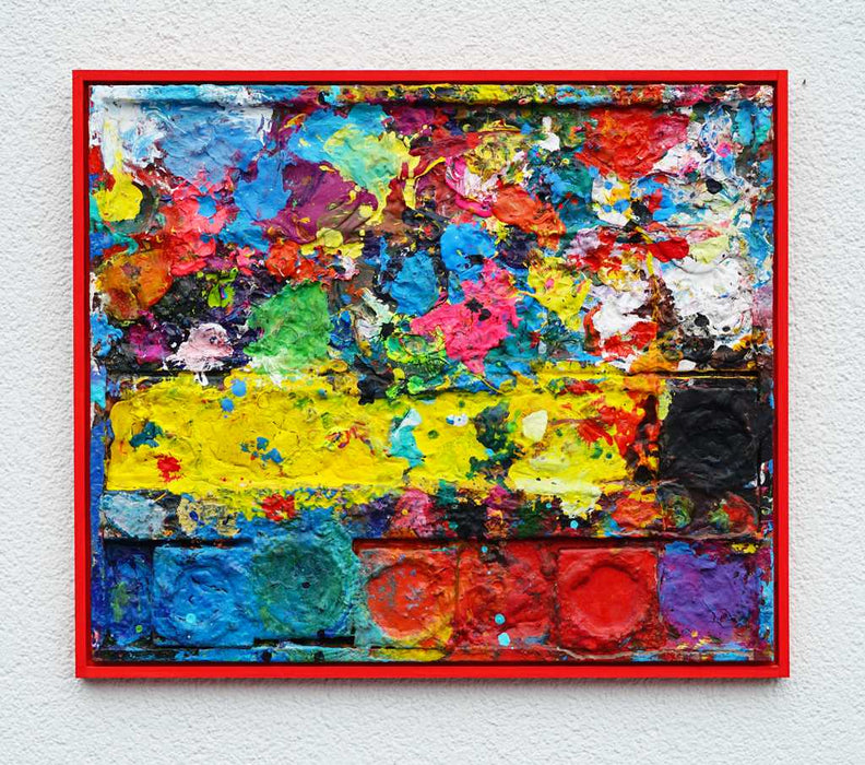 "Arena" zeigt moderne Malerei auf dem Farbkasten (eingerahmt 54 x 64 cm) und ergibt ein Wandobjekt. In den Mischfächern (rechts) sind bunte Farbtöne und -kleckse zu erkennen. In der linken Hälfte befinden sich 5 Farbteller mit Rot, Orange, Grün, Blau und Schwarz. In den Zwischenräumen sind Farbflecken sichtbar. Es wurde experimentell gemalt. Das Gemälde ist mit Schattenfuge gerahmt. Das Original befindet sich in Wiesbaden bei Frankfurt. Abstrakte Kunst. ARTLET | Atelier Hellbusch.