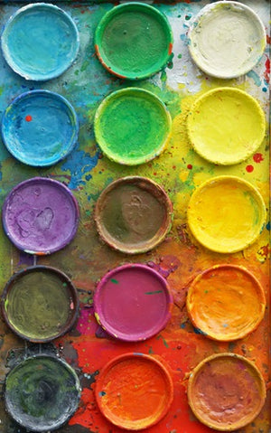 "Die Reise" zeigt bunte Malerei auf einem überdimensionierten Farbkasten (100 x 200 x 4 cm). Hier ist ein Ausschnitt davon zu sehen. In den Mischfächer (außen) sind blaue, violette, grüne, gelbe und graue Farben zu sehen. In der Mitte befinden sich 15 Farbteller mit den üblichen Farben einer Palette. In den Zwischenräumen sind Farbkleckse und -flecken sichtbar. Großformatige Kunst. ARTLET | Atelier Hellbusch