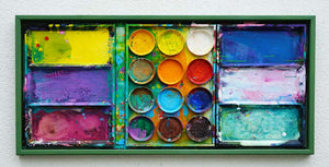 "Jungle" zeigt abstrakte Malerei auf dem Farbkasten (eingerahmt 65 x 135 cm) und ergibt ein Wandobjekt. In den Mischfächern (rechts) sind blaue und weiße Farbtöne zu erkennen. Ganz links Gelb, Violett und Bordeaux. In der Mitte befinden sich 12 Farbteller mit den typischen Farben der Palette. In den Zwischenräumen sind Farbkleckse und -flecken sichtbar. Es wurde experimentell gemalt. Moderne Kunst. ARTLET | Atelier Hellbusch.