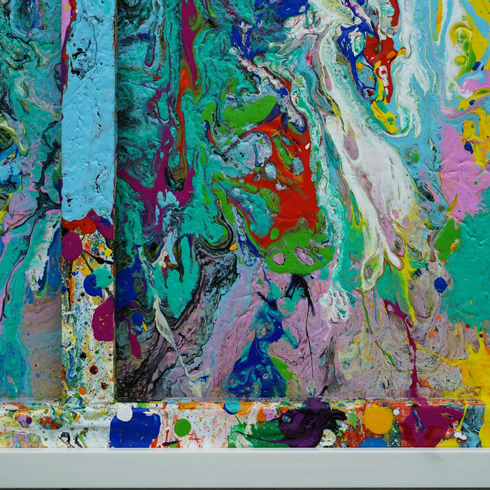 RE 21 zeigt ein abstraktes Farbrelief aus Türkis, Rosa, Gelb, Schwarz und Weiß – entstanden aus aufgefangener Farbe, gerahmt in Weiß mit räumlicher Tiefe (Nahaufnahme). Atelier Hellbusch.