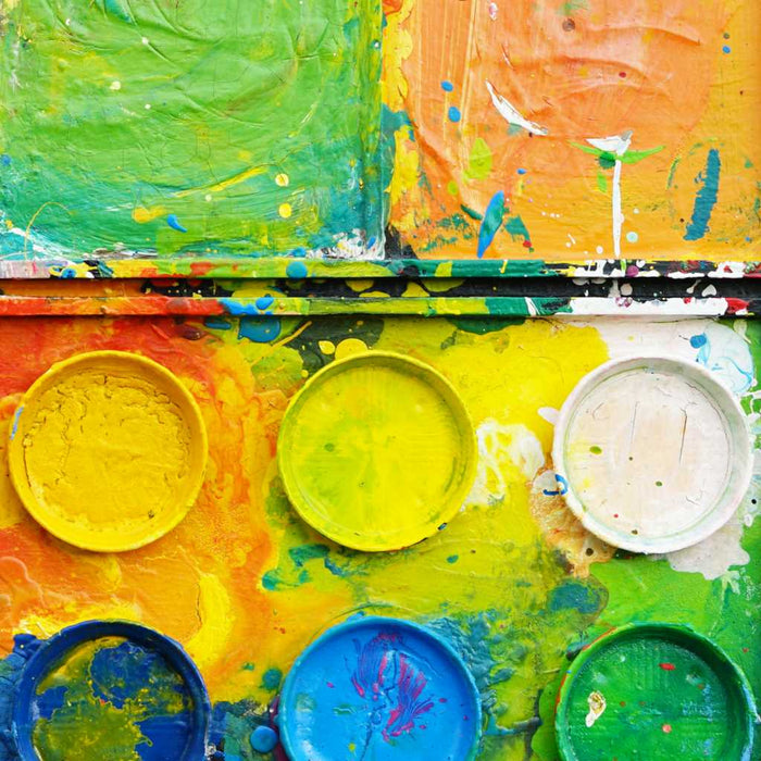 "Der Sommer" zeigt moderne Kunst auf dem Farbkasten (80 x 110 cm, Nahaufnahme). In den Mischfächer (unten) sind bunte Farben zu sehen: orange, grün, blau und gelb. Oben befinden sich 12 Farbteller. In den Zwischenräumen sind Farbkleckse und -flecken sichtbar. Die Malerei wurde experimentell umgesetzt. Abstraktes Gemälde. ARTLET - Atelier Hellbusch.