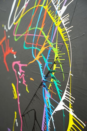 Experimentelles Gemälde auf runder Leinwand mit lebendigen Farbspritzern auf schwarzem Hintergrund. Seitenperspektive. ARTLET - Atelier Hellbusch