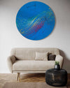 "Splash 65" (in situ), ein rundes Gemälde mit einem Durchmesser von 120 cm, zeigt eine lebendige Mischung aus blauen, roten, gelben, grünen und weißen Farbspritzern, die Dynamik und Eleganz vereinen. Kunstwerk des Atelier Hellbusch.