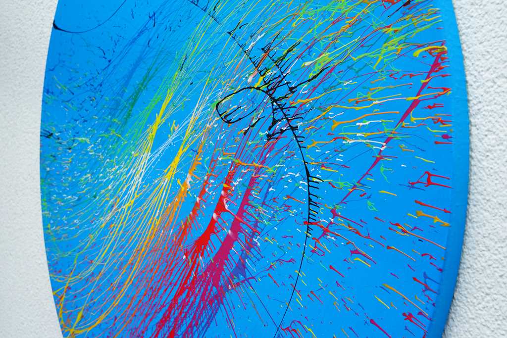 "Splash 65" (Seite), ein rundes Gemälde mit einem Durchmesser von 120 cm, zeigt eine lebendige Mischung aus blauen, roten, gelben, grünen und weißen Farbspritzern, die Dynamik und Eleganz vereinen. Kunstwerk des Atelier Hellbusch.