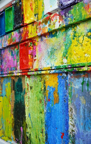 "Stillleben mit Blumen" zeigt moderne Kunst als Wandskulptur (86 x 96 cm), aus der Seitenperspektive. Zu sehen ist das Gemälde in Wiesbaden. In den Farbtellern (oben) sind Gelb, Grün, Schwarz, Violett, Weiß und Blau zu sehen. Unten befinden sich 5 Mischfelder ebenfalls mit bunten Farben. In den Zwischenräumen sind Farbkleckse und -flecken sichtbar. Moderne Kunst von Mark Hellbusch. ARTLET | Atelier Hellbusch.
