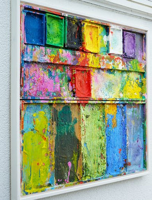 "Stillleben mit Blumen" zeigt moderne Kunst als Wandskulptur (86 x 96 cm) aus der Seitenperspektive. Zu sehen ist das Gemälde in Wiesbaden. In den Farbtellern (oben) sind Gelb, Grün, Schwarz, Violett, Weiß und Blau zu sehen. Unten befinden sich 5 Mischfelder ebenfalls mit bunten Farben. In den Zwischenräumen sind Farbkleckse und -flecken sichtbar. Moderne Kunst von Mark Hellbusch. ARTLET | Atelier Hellbusch.
