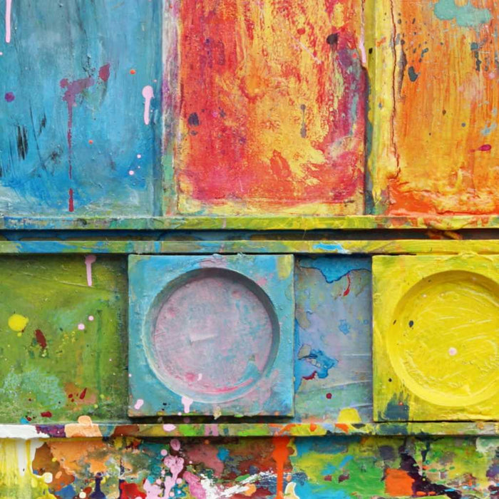 "Unterwegs III" zeigt zeitgenössische experimentelle Malerei (92x80x3 cm) auf einem Wandobjekt (Farbkasten). In den Mischfächer (unten) sind blaue, orangene, gelbe, weiße, schwarze und pinke Farben zu sehen. Oben befinden sich 9 Farbteller mit den üblichen bunten Farben eines Farbkastens. In den Zwischenräumen sind Farbkleckse und -flecken sichtbar. Diese experimentelle Malerei - schön, bunt und modern - kann man zum realistischen Preis online bestellen. Zeitgenössische Malerei. ARTLET - Atelier Hellbusch