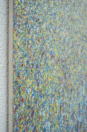 Kunstwerk 'Claim 107' (90x130 cm) von Mark Hellbusch, 2024, zeigt eine dichte, lebendige Anordnung von Farbspritzern in Blau, Gelb und Violett. Diese abstrakte Komposition erzeugt eine faszinierende visuelle Textur, die die Energie und Kreativität des Künstlers widerspiegelt (Seitenansicht).