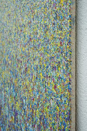 Kunstwerk 'Claim 107' (90x130 cm) von Mark Hellbusch, 2024, zeigt eine dichte, lebendige Anordnung von Farbspritzern in Blau, Gelb und Violett. Diese abstrakte Komposition erzeugt eine faszinierende visuelle Textur, die die Energie und Kreativität des Künstlers widerspiegelt (Seitenansicht).