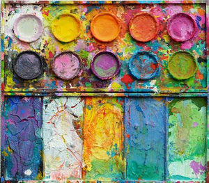"In den Bergen" zeigt moderne Kunst auf dem Farbkasten (64 x 72 cm). In den Mischfächer (unten) sind bunte Farben zu sehen: Frühlingsfarben in orange, grün, blau, violet und weiß. Oben befinden sich 10 Farbteller mit der typisch bunten Palette der Farben eines Farbkastens. In den Zwischenräumen sind Farbkleckse und -flecken sichtbar. Die Malerei wurde experimentell umgesetzt. Abstrakte Malerei. ARTLET | Atelier Hellbusch.