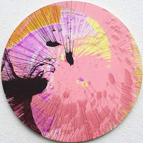 Splash 29 | Modernes Kunstwerk auf runder Leinwand (Durchmesser 80 cm). Das Gemälde ist bunt mit Pink als dominante Farbe. Außerdem sind Gelb, Orange und Schwarz in einer schwungvollen, abstrakten Komposition zu sehen. Die Malerei ist rein experimentell. Präsentiert und fotographiert an der Außenmauer des Ateliers Hellbusch. Modernes Gemälde auf bunte, abstrakte Art. Modernes Kunstwerk. ARTLET | Atelier Hellbusch